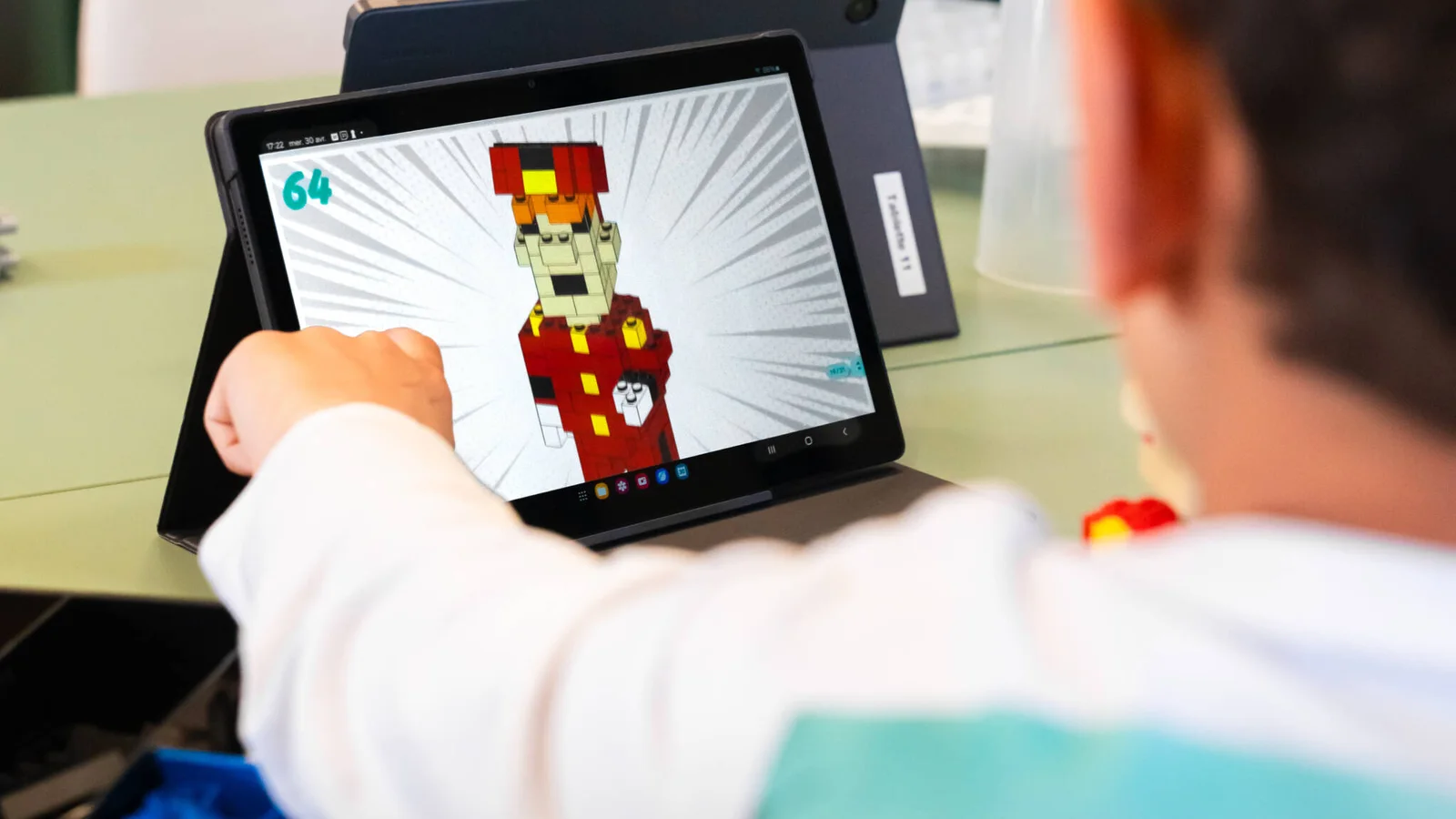 Enfant suivant un modèle de construction en briques LEGO® sur tablette, atelier Bricks Factory à Vedène